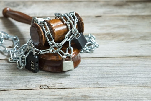 A gavel sits on a table and has chains around it.