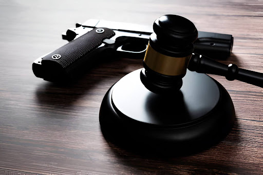 A gun is sitting on a desk next to a gavel.